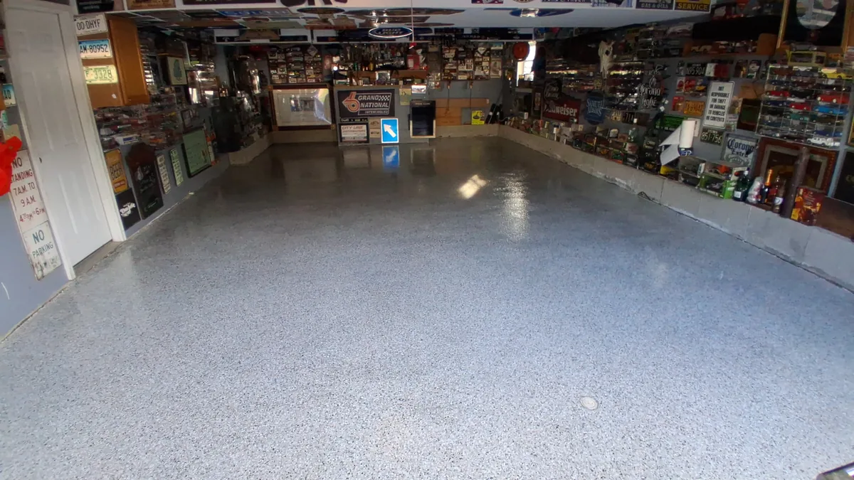 A finished gray flake floor across a two-car garage lined with signs and model cars
