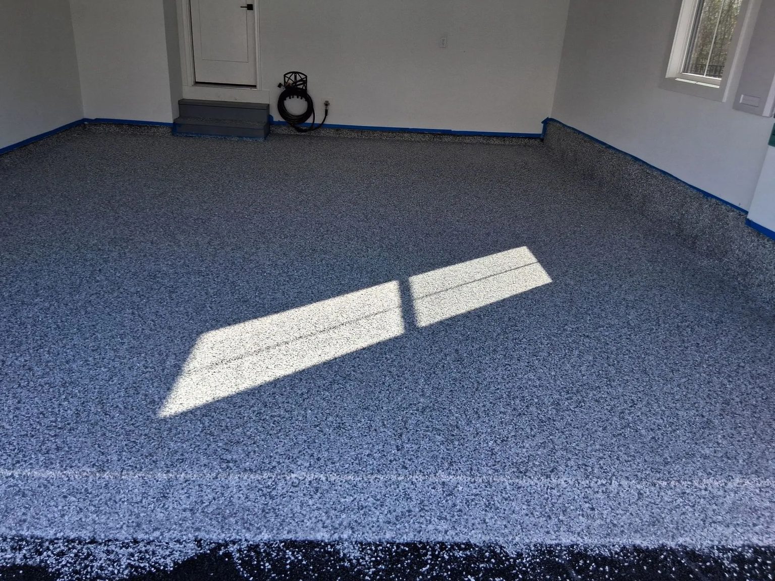 A finished flake floor in a garage with the door open and sun across it